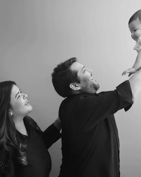 A moment of pure joy and connection as a father lifts his baby high in the air, with mom looking on lovingly. These black and white family portraits are timeless.