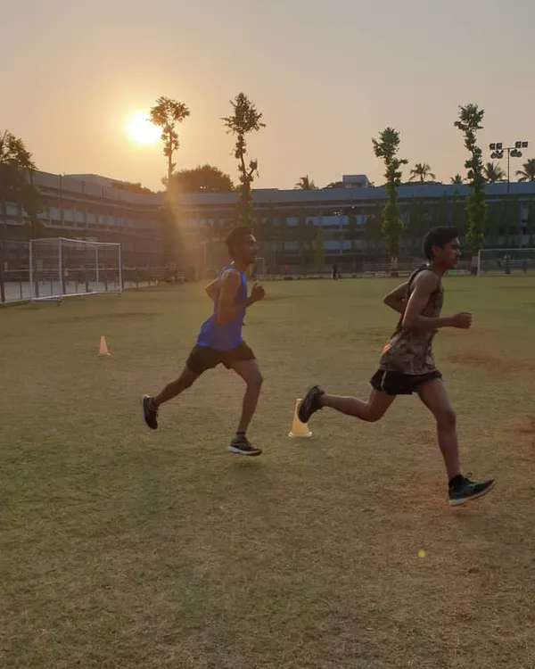 Two athletes executing a running drill against a sunset backdrop, embodying our philosophy to "run like no one's watching."