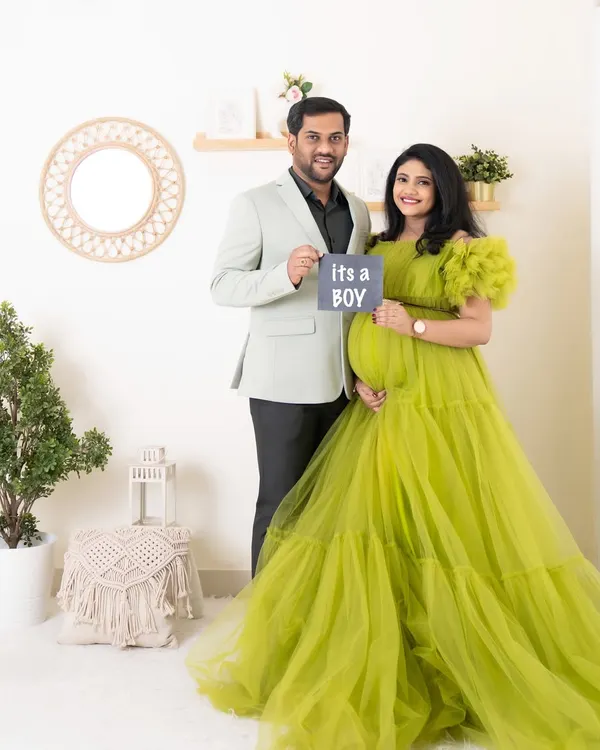 A happy couple announces "It's a boy!" during their studio maternity session. The mother-to-be looks stunning in a vibrant green tulle gown I provided for the shoot.