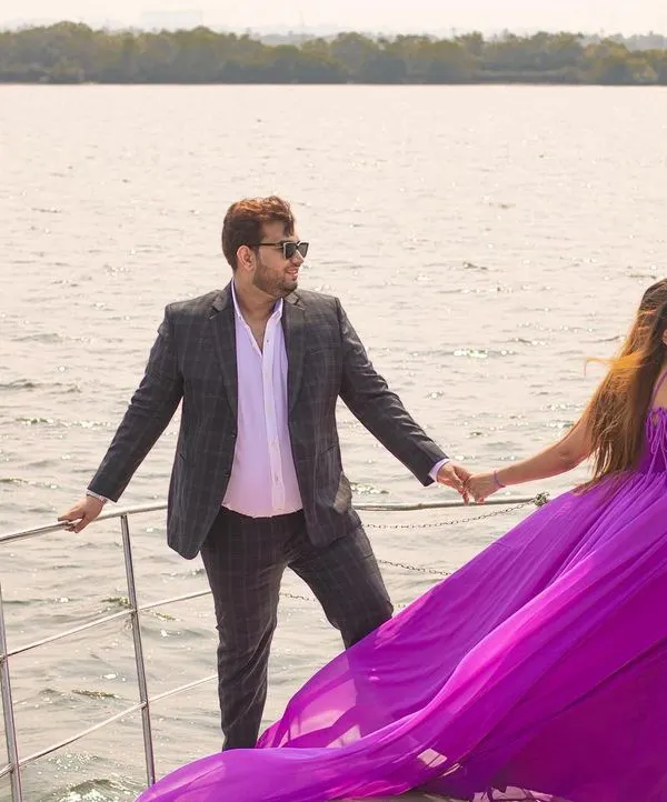 A stunning shot of the couple on a private yacht in Goa, with the bride's vibrant purple gown flowing in the wind. This is the essence of a luxurious destination pre-wedding shoot.