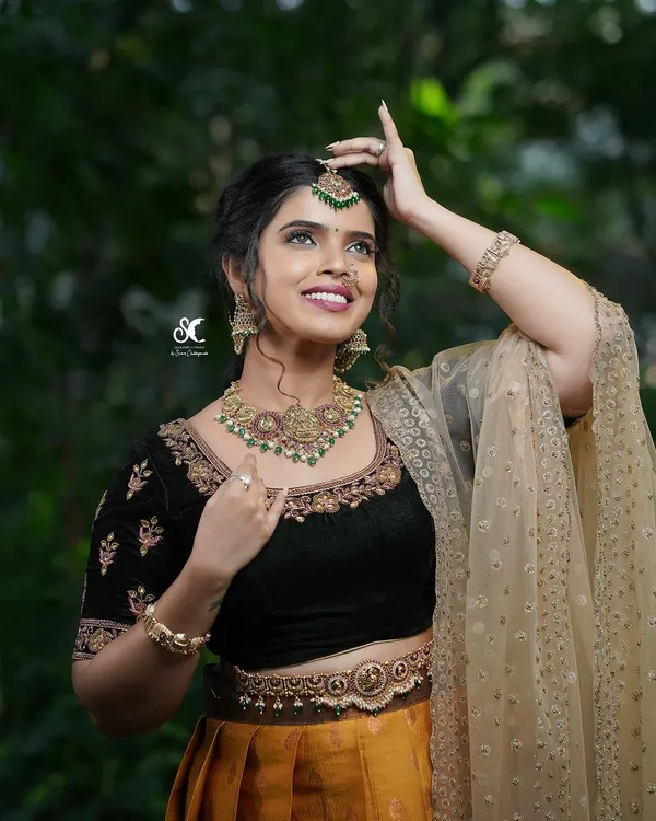 A beautiful portrait for a makeup artist's portfolio. The model's joyful expression and the rich details of her traditional attire are captured in soft, natural light.
