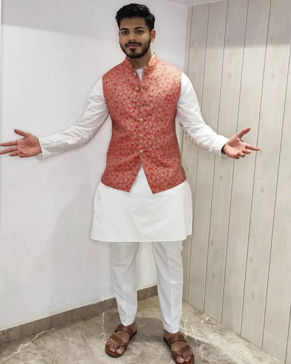 A classic white kurta-pajama set styled with a vibrant floral Bandi jacket. The white base is versatile, allowing you to pair it with jackets of any color for different functions.