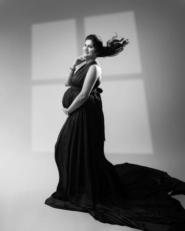 Unveiling the elegance and grace of motherhood in a timeless monochrome moment. The flowing gown and serene smile create a work of art that transcends time.