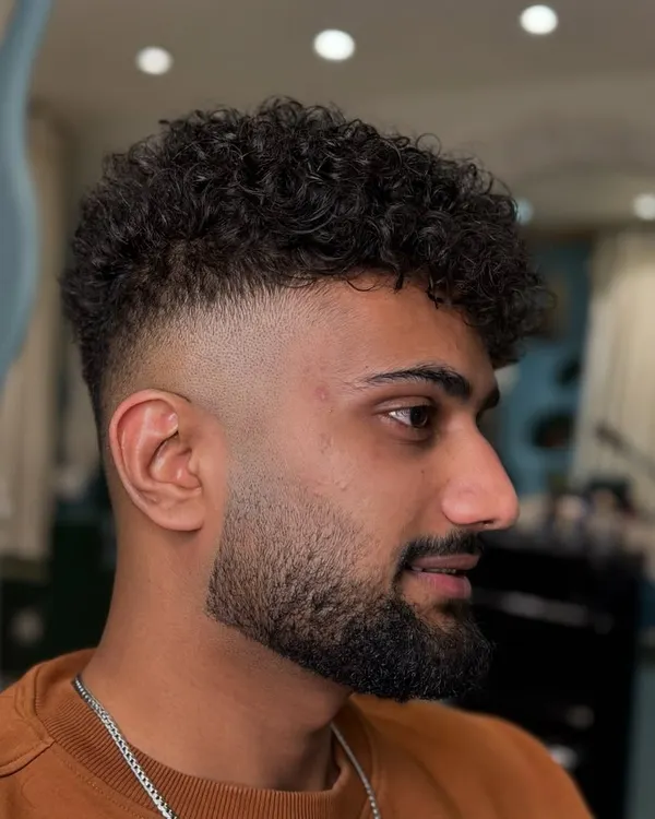 This is what we do best. A perfect high fade blended into natural curls, finished with a sharp beard line-up. It's a modern, clean, and stylish look.
