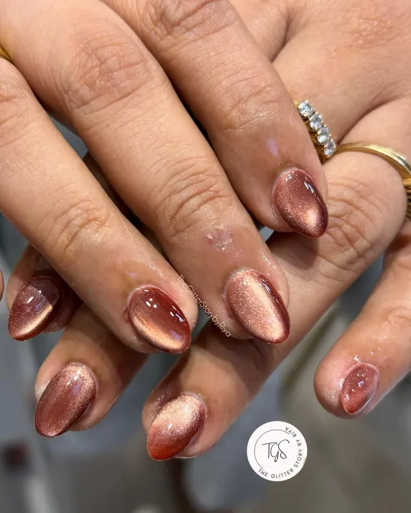 A beautiful set of almond-shaped nails with a reddish-brown cat-eye effect. The magnetic polish creates a stunning light-reflecting band that moves across the nail.