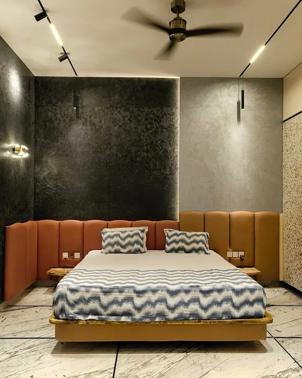 The master bedroom in our "House Reversed" project features an exotic, shimmering matrix stone wall, complemented by a warm leather headboard and dramatic lighting.
