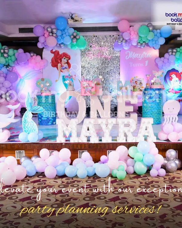 I bring underwater fantasies to life with breathtaking mermaid-themed decorations. This setup for a first birthday features custom marquee letters, intricate balloon sculptures of a whale and mermaid tail, and a sparkling backdrop to create a truly magical ocean world.