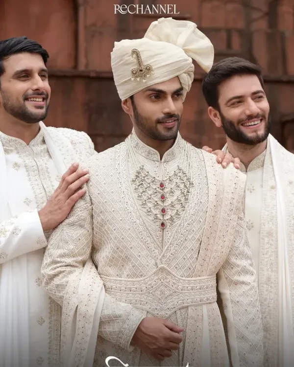 A professional editorial shoot featuring natural grooming for men. The focus is on clean skin, defined brows, and neat hair to create a polished look for these traditional sherwanis.