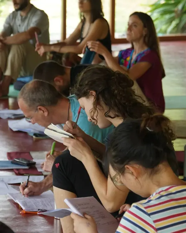 Our teacher training is not just about physical postures; it's an academic and spiritual inquiry. Students are deeply focused during a yoga philosophy lecture, taking notes to absorb the timeless wisdom of the practice.