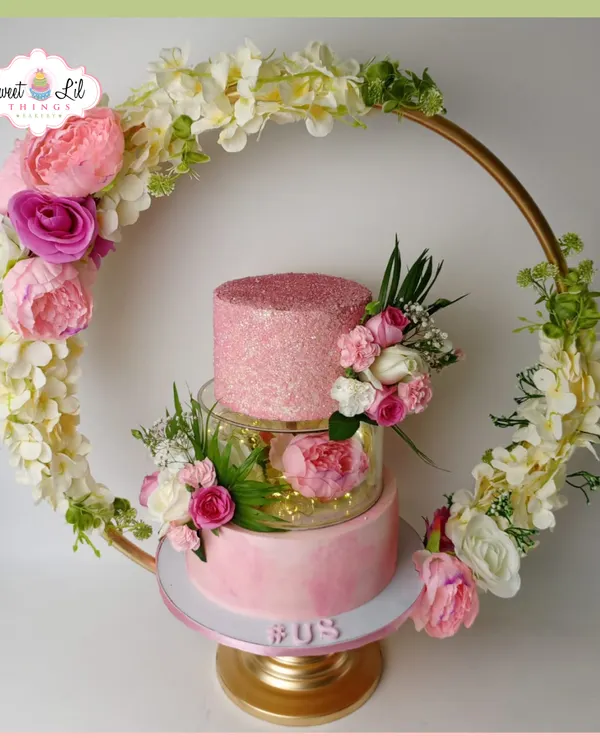 This is one of my favorite creations, a stunning pink tiered cake framed by a floral hoop. It combines modern design with classic elegance, featuring a sparkling top tier, a translucent separator with fairy lights, and a cascade of handmade sugar flowers, making it a true centerpiece for a wedding or a grand celebration.