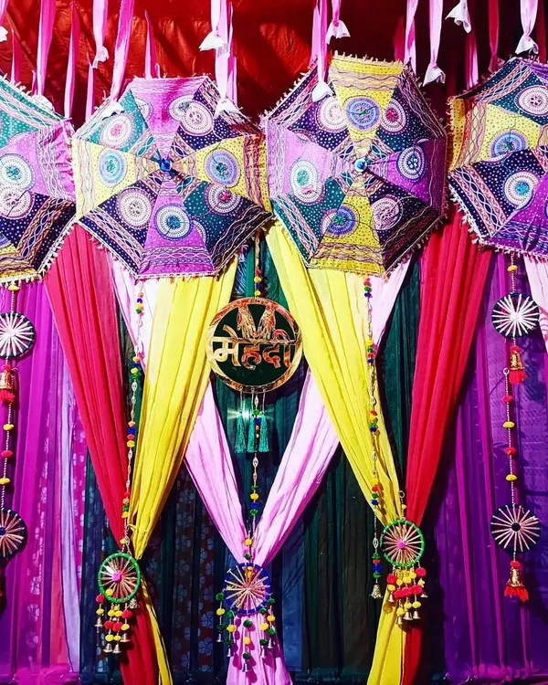 This Mehndi backdrop is all about vibrant colors and traditional charm. I used colorful drapes in pink, yellow, and green, and hung decorative Rajasthani umbrellas to create a festive and joyful photo corner.