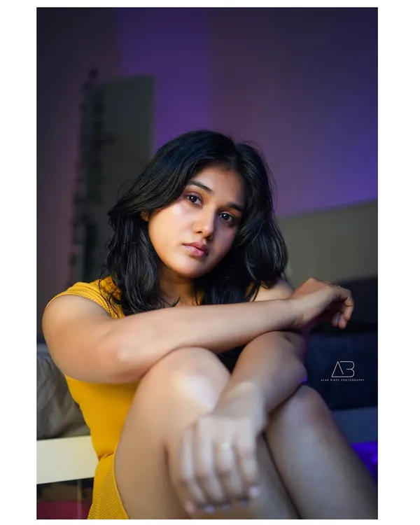 An intimate, moody portrait. The purple ambient light and soft shadows create a cinematic feel, drawing all the attention to her expressive gaze. This is a perfect example of an indoor, story-driven shot.
