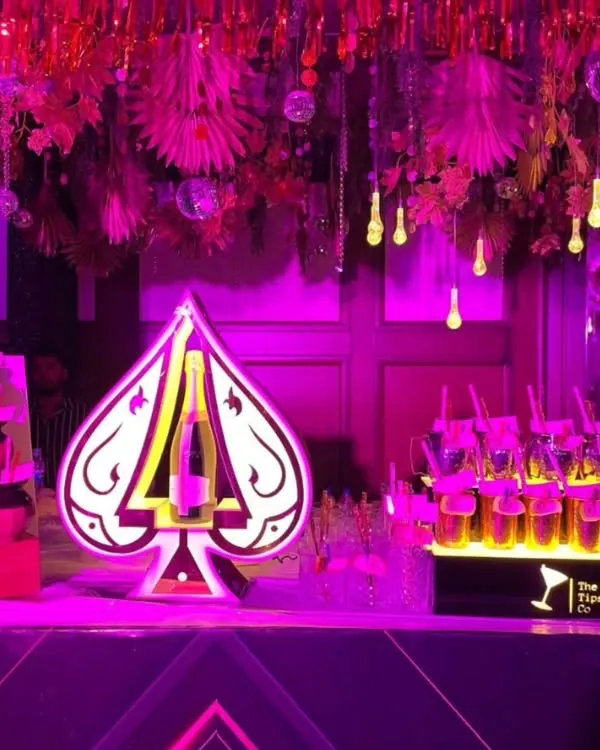 For this event, we created a glamorous bar setup featuring a custom 'Ace of Spades' light installation. The vibrant pink lighting and disco ball decor transformed the space into a high-energy party zone.