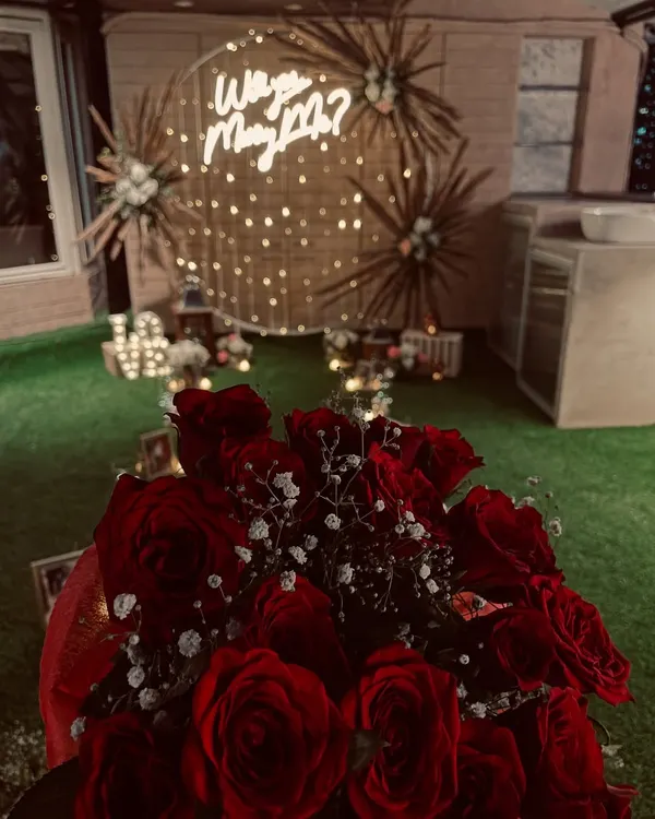 I was honored to be a part of this magical moment. A beautiful bouquet of red roses in the foreground of a romantic "Will you Marry Me?" proposal setup I helped create.