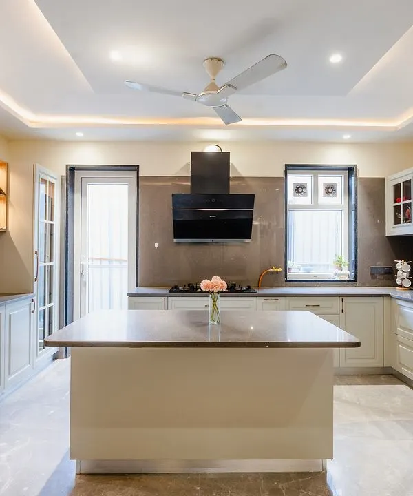 This island kitchen is a masterpiece of modern design. The off-white shaker-style cabinets give it a timeless, classic feel, while the large island provides ample workspace and casual seating. The space is bright and airy, thanks to the large window and uPVC door.