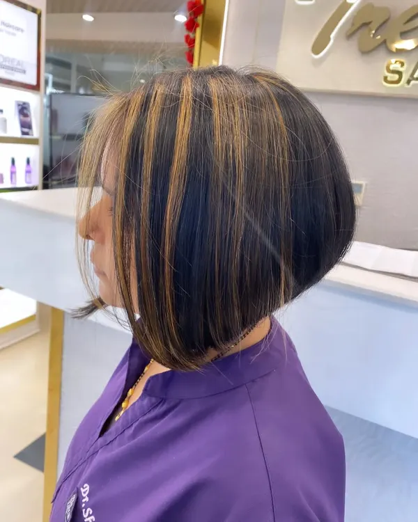 A chic and trendy angled bob haircut. We added bold blonde highlights to make the sharp lines of the cut stand out.