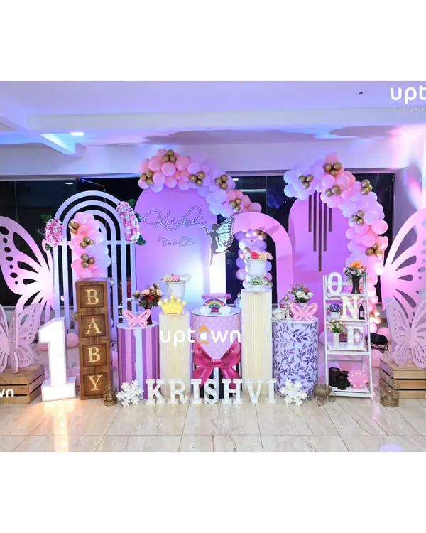 A beautiful butterfly theme for Krishvi's first birthday, using shades of purple and pink with large butterfly wing cutouts.