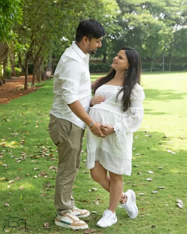 A sweet and casual moment between a couple in a beautiful green park. Their coordinated white outfits and happy smiles create a fresh and natural portrait.