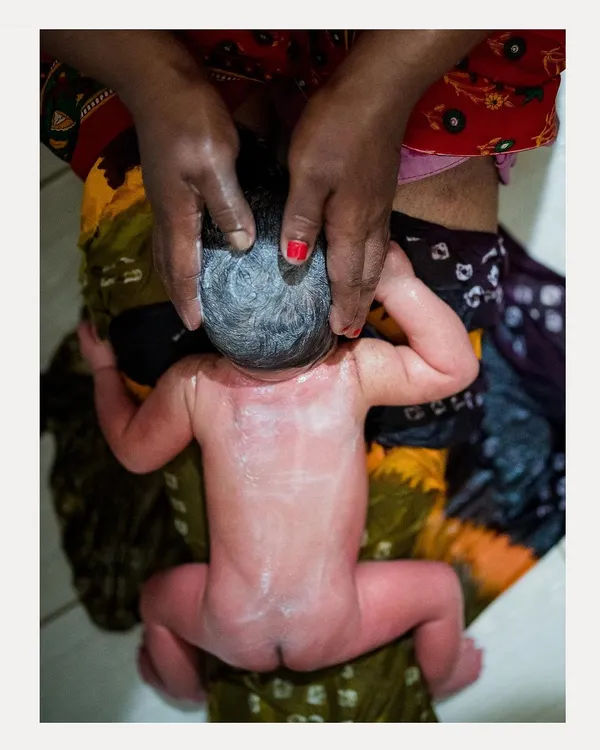 An overhead view of a traditional newborn oil massage, a moment of pure, tender care. We document these intimate rituals with respect and artistry, focusing on the loving touch.