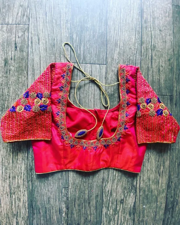 A pink raw silk blouse with a square neckline. The embroidery on the sleeves is done with blue and gold thread for a nice contrast.