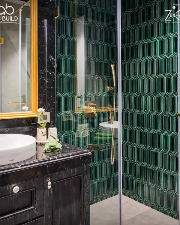 This bathroom in 'The House of Arcs' features striking emerald green geometric tiles, black marble, and brushed gold fixtures. The design is bold and luxurious, creating a dramatic and memorable space.