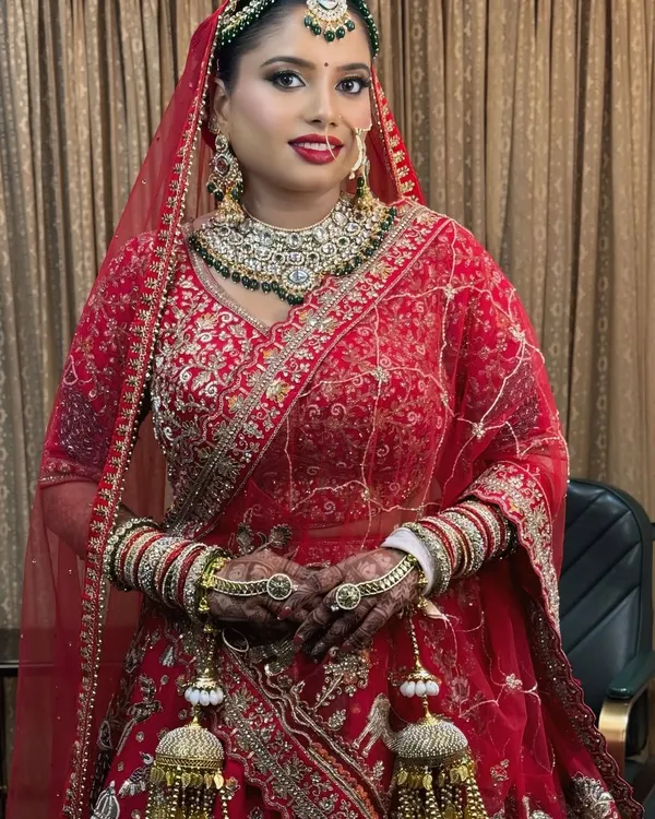 A full-length view of this stunning bride in her traditional red lehenga. The makeup is designed to be sweat-proof and picture-perfect, lasting through the entire ceremony.