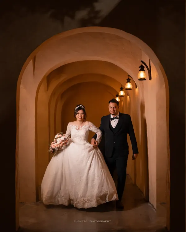 A fairytale entrance. The couple walks hand-in-hand through a warmly lit archway, beginning their life together.