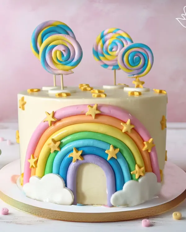 A vibrant and cheerful rainbow cake, decorated with fondant stars, clouds, and colorful lollipops. This cake is a pure slice of happiness, perfect for a bright and joyful celebration.