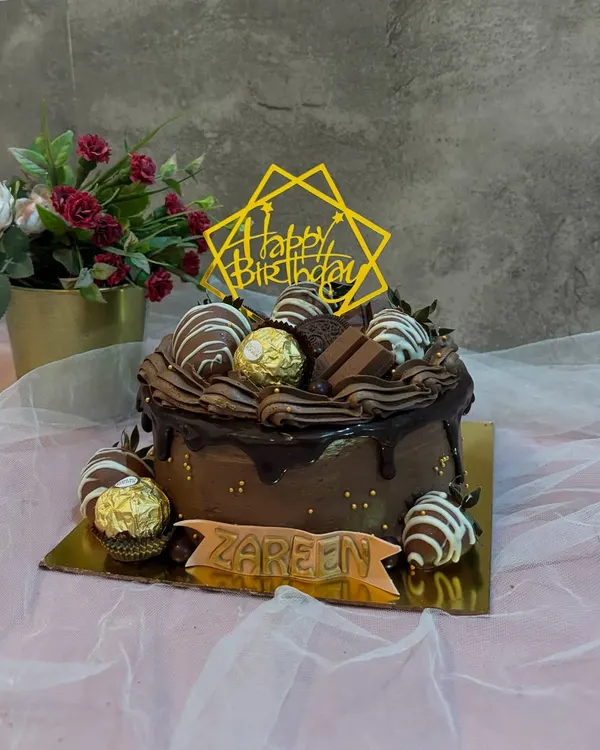 My bestseller, the Belgian Chocolate and Strawberry cake. This rich chocolate drip cake is topped with chocolate covered strawberries, Ferrero Rocher, and KitKat pieces.