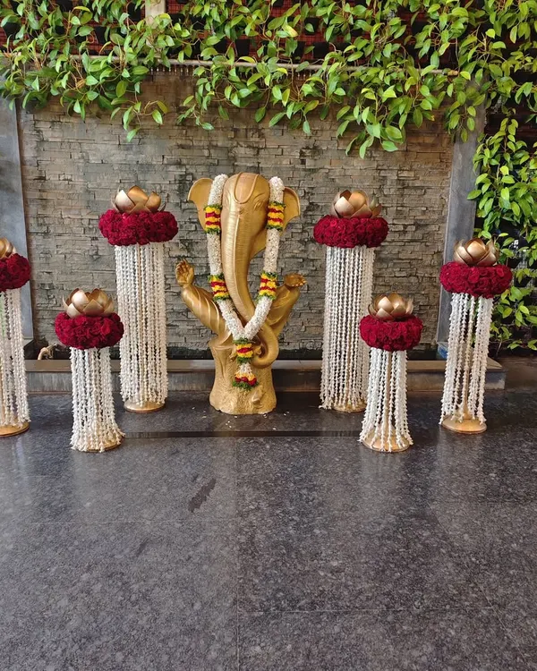 A sacred corner featuring a Ganesha idol, adorned with floral garlands and surrounded by traditional brass lamps and flower arrangements to welcome guests with blessings.