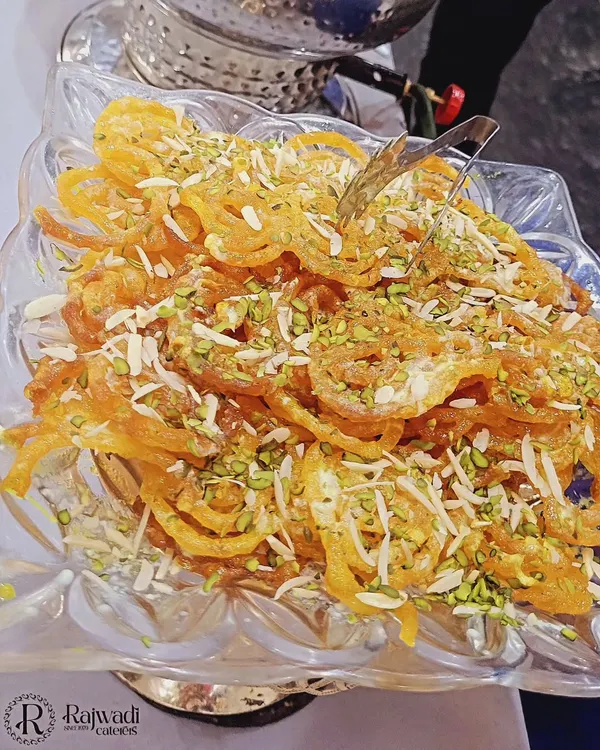 A close-up of my perfectly crisp and syrupy jalebi, garnished with chopped pistachios and almonds. It’s a classic dessert that I make fresh for my events.