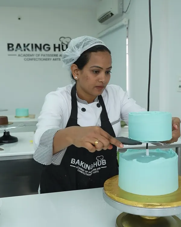 A student carefully stacking a two-tier cake. We teach the crucial techniques for structure and stability, ensuring you can confidently create multi-layered cakes that are both beautiful and secure for transport.