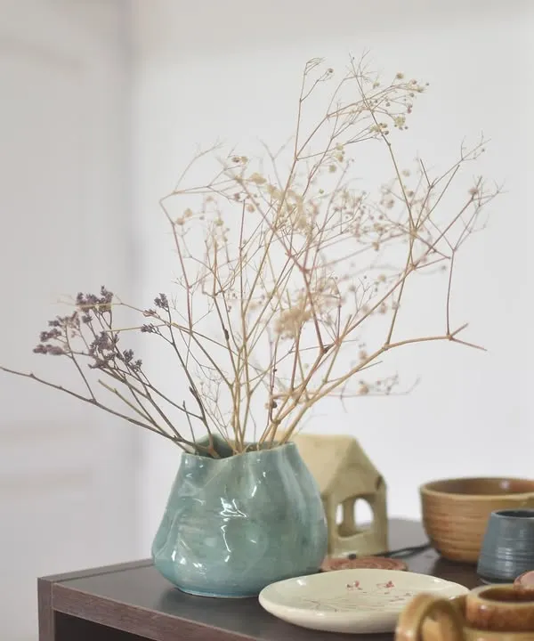 A beautiful, organically shaped vase made by a student, now holding delicate dried flowers. Simple and elegant.