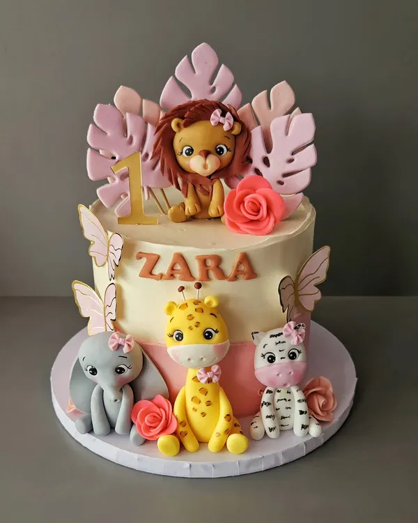 All things pink and pretty for Zara's first birthday. This jungle cake features adorable, hand-sculpted baby animals like a lion, giraffe, elephant, and zebra, all with cute pink bows.