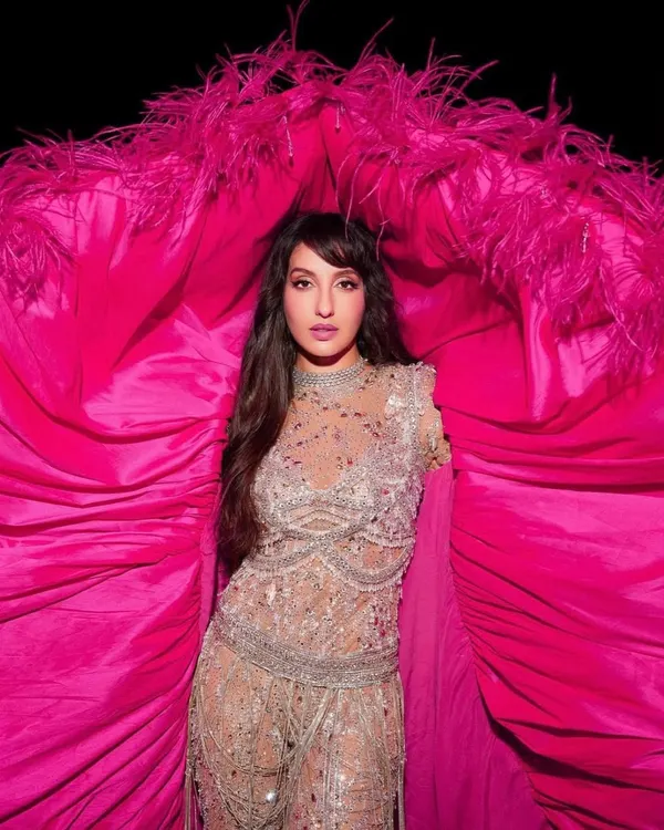 A close-up of Nora Fatehi's FIFA World Cup performance look. The intricate beadwork on the Falguni Shane Peacock catsuit is visible here, framed by the vibrant pink cape.