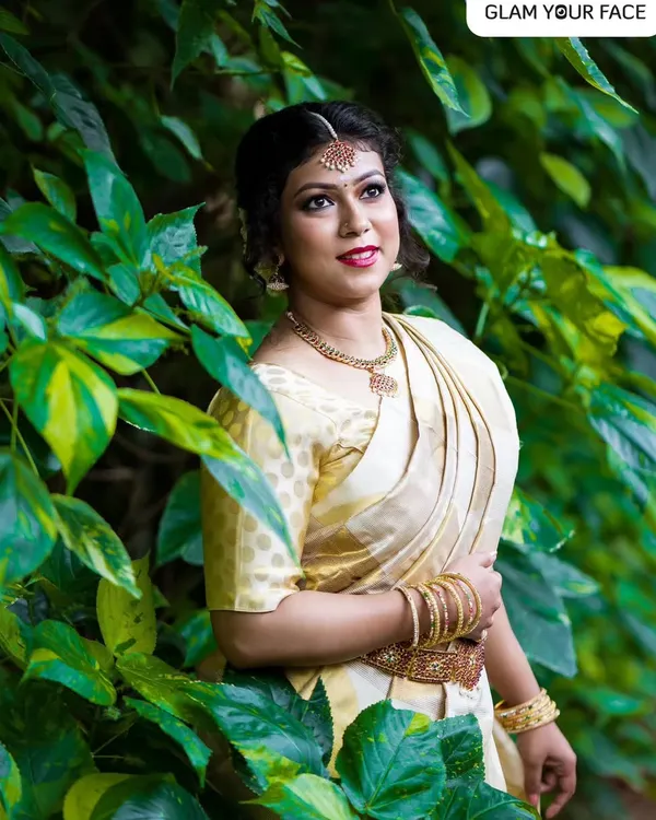 This look captures the beautiful traditions of Onam. I created a minimalistic makeup look with a bold red lip and paired it with a floral messy bun to complement the classic Kasavu saree. It’s all about celebrating with elegance.