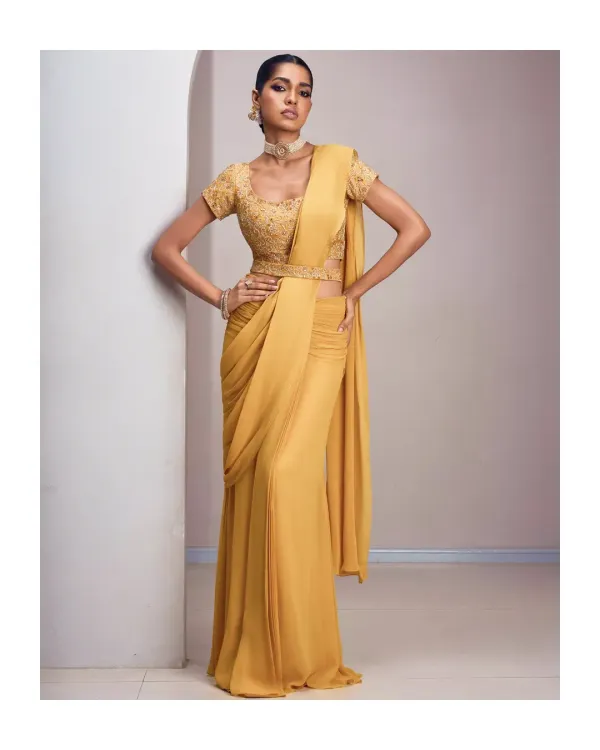 A modern drape in a sun-kissed yellow hue exudes confidence and effortless style. This pre-draped saree is perfect for those who love the elegance of a saree but prefer a fuss-free, contemporary silhouette for festive events.