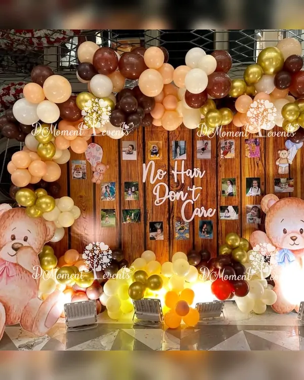 A fun and heartwarming photo wall for a Mundan ceremony. The "No Hair Don't Care" sign adds a playful touch to the teddy bear theme, which features a wood-panel backdrop and earthy-toned balloons.