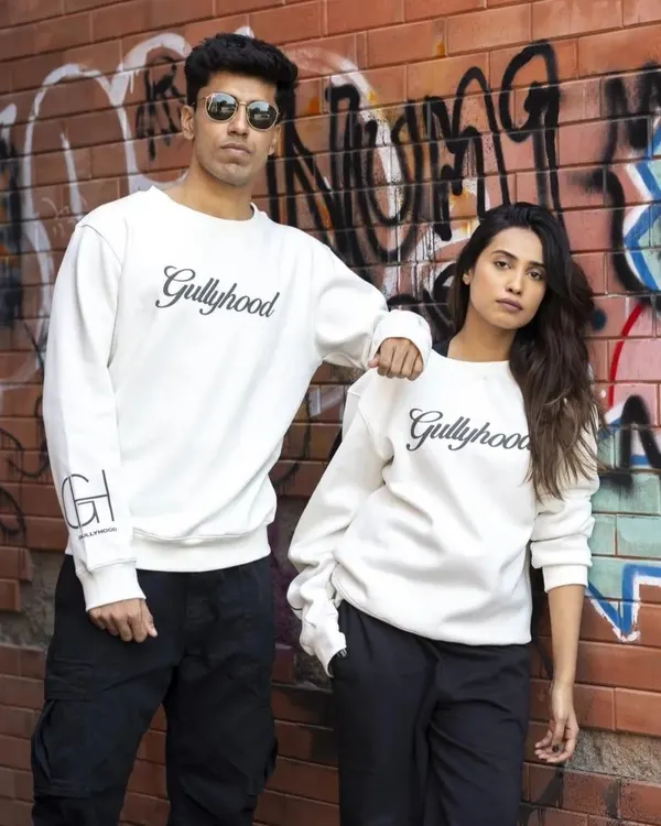 A duo shot for a streetwear brand, featuring matching sweatshirts against a graffiti wall. This image establishes a cool, urban aesthetic and is great for showing unisex apparel.