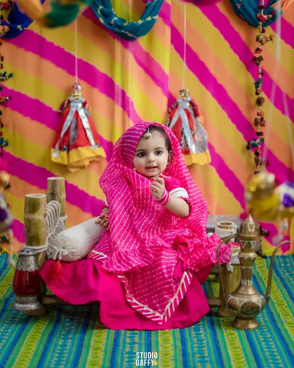 A little Rajasthani princess in a vibrant pink leheriya outfit. We created this entire set to celebrate her milestone with cultural richness and bright, joyful colors.