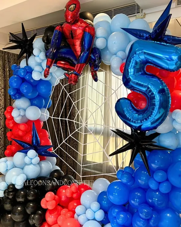 An action-packed Spider-Man setup for a 5th birthday. The circular balloon arch in red, blue, and black perfectly frames the web backdrop, with the hero himself ready for action.