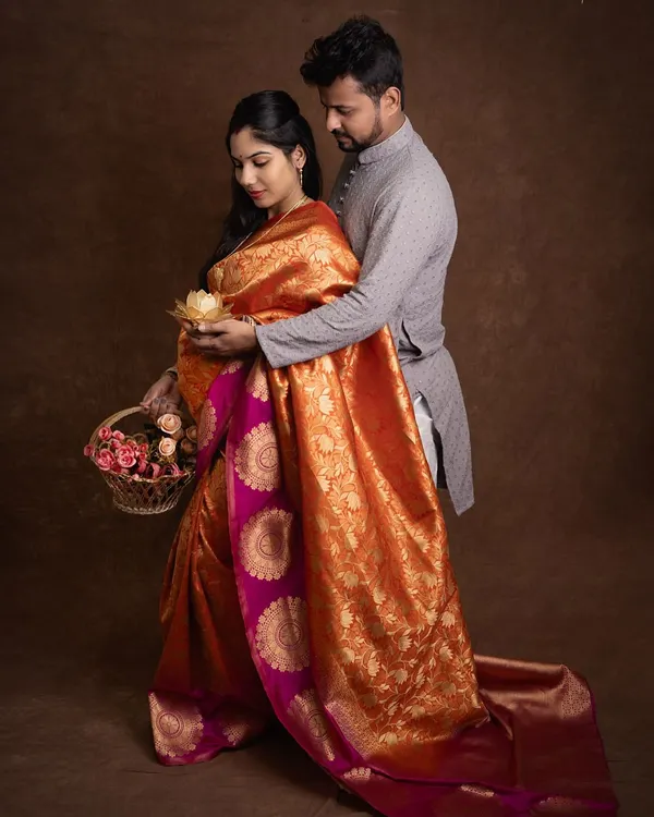 A beautiful moment from a traditional maternity shoot. The rich silk saree, the basket of flowers, and the gentle way he holds her create a picture of timeless love.