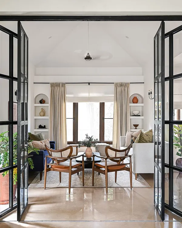 This view, through custom black iron French doors, captures the essence of my design philosophy. It’s about creating open, inviting living spaces that feel both grand and intimate, blending classic architectural elements with modern comfort for a truly timeless home.
