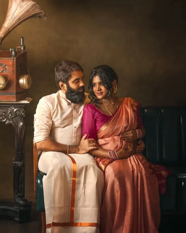 A vintage-themed studio portrait capturing the intimate connection between a couple. Their traditional attire and the classic props create a timeless image of their shared journey.