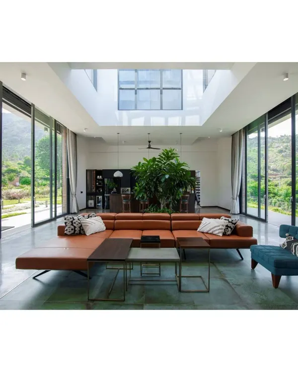 This weekend home at Nandi Hills is designed to be a sanctuary, seamlessly blending indoor comfort with the breathtaking landscape. The open-plan living area features floor-to-ceiling glass walls and a central skylight, inviting natural light and panoramic views deep into the heart of the home.