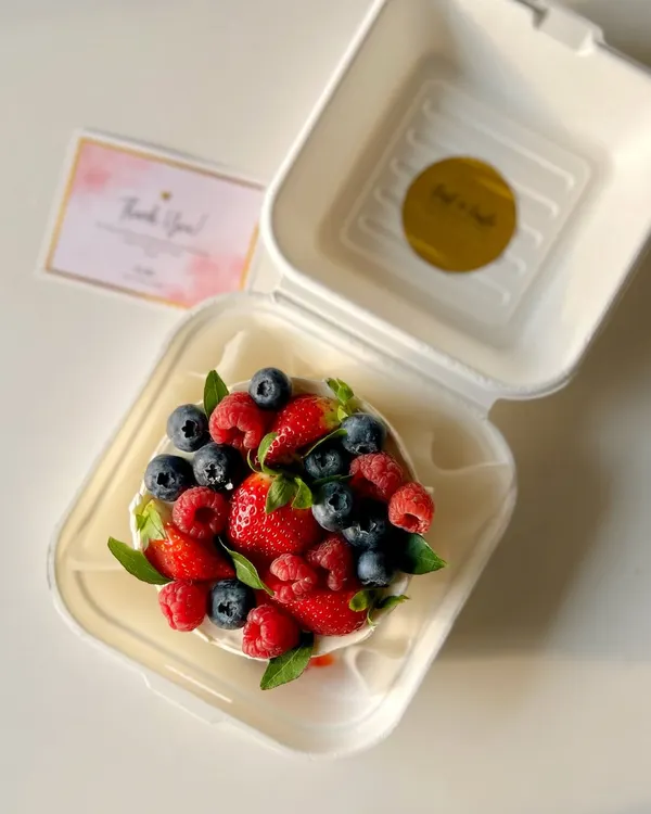 An overhead shot of my seasonal berry-loaded bento cake. It's generously topped with fresh strawberries, blueberries, and raspberries for a burst of flavor and color.