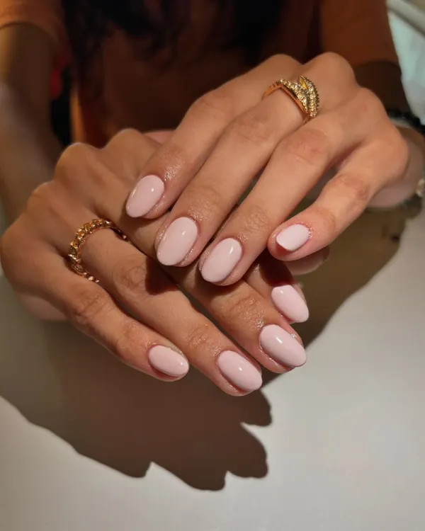 A perfect example of timeless elegance. This manicure features a classic, clean nude-pink polish on beautifully shaped short, oval nails for a look that is effortlessly chic and sophisticated.