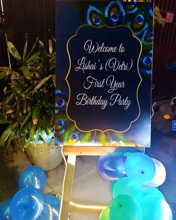 Welcome your guests in style with a custom-designed welcome board. This one was created for a peacock-themed party, featuring elegant script and a beautiful feather design.