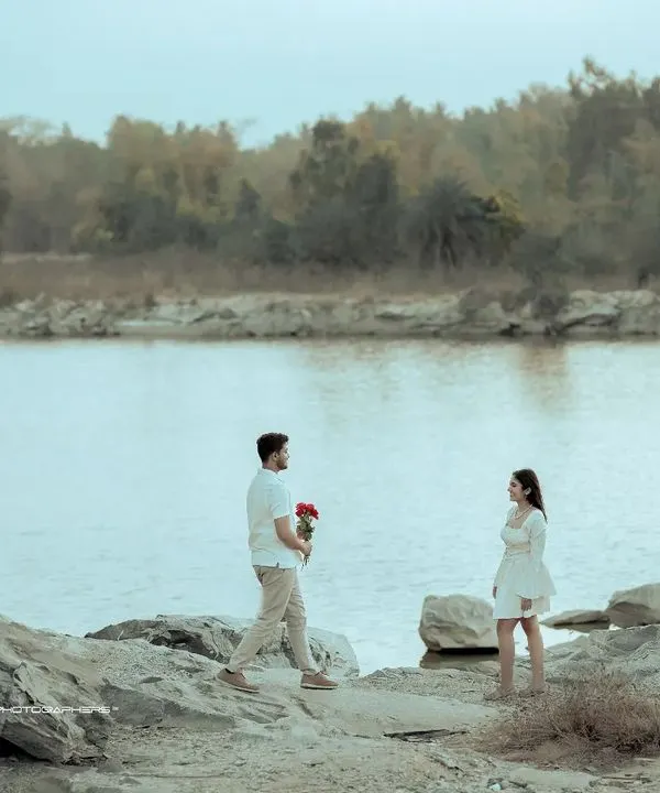 A classic romantic gesture. The groom approaches with flowers against a vast, tranquil lake, creating a scene straight out of a storybook for this pre-wedding shoot.