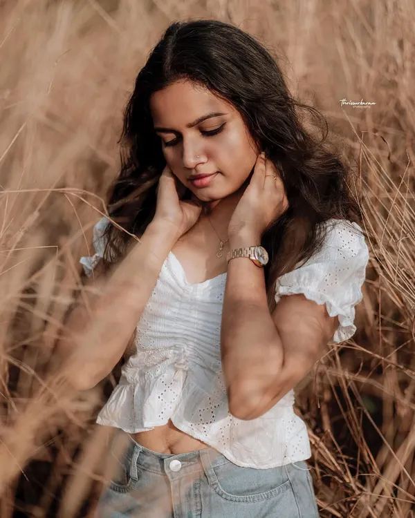 A soft, naturally lit portrait in a field of tall grass. The warm tones and the model's gentle expression create a serene and beautiful image.
